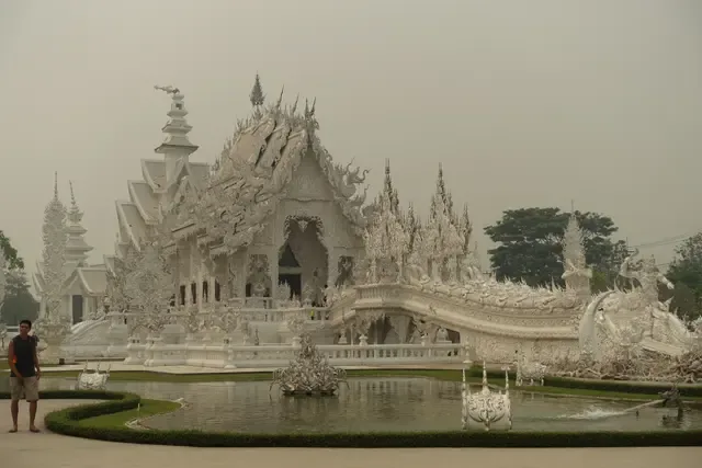Ornate white temple reflected beside a garden pond