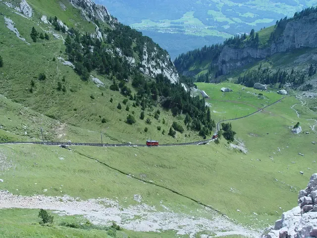 Mountain valley with a railway crossing green slopes
